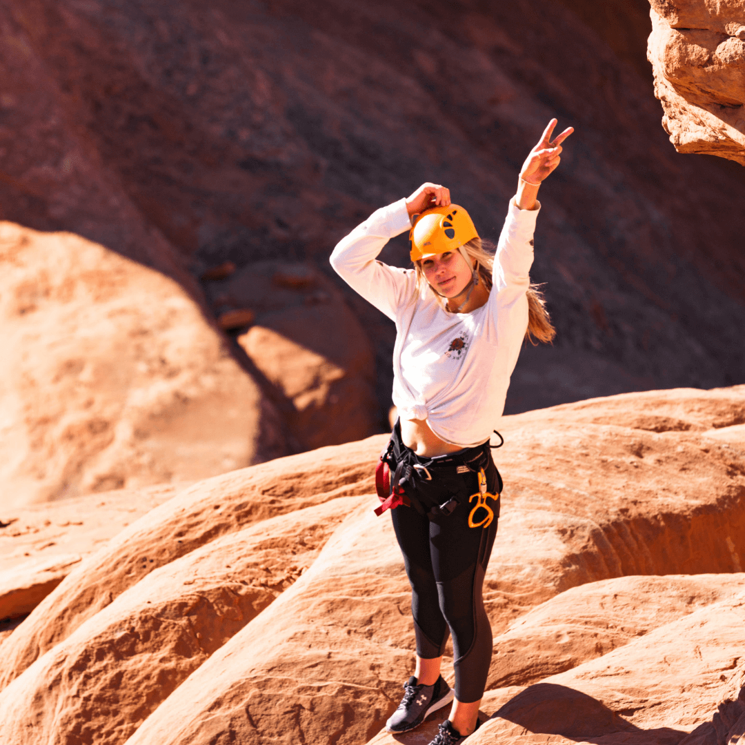 Young woman smiling while enjoying a day climbing in Arches National Park in Utah.
