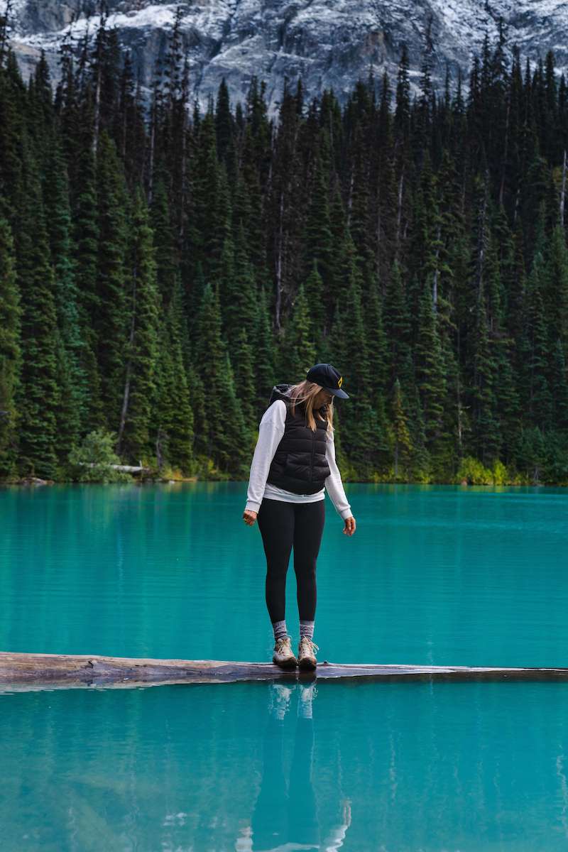 Woman standing on floating log with mountain background at Joffre Lakes in Briths Columbia