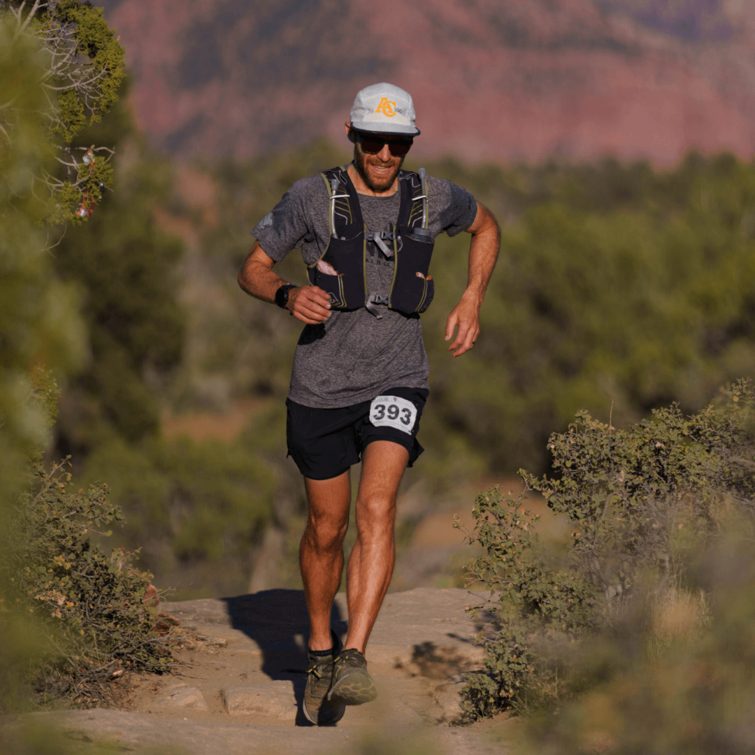 Young man running with desert landscape for the Zion Ultra 100 marathon race by Ultra Adventures in Utah